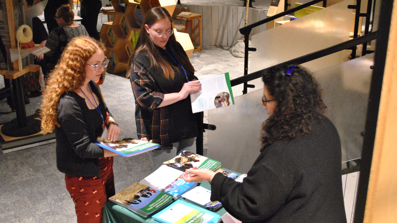 Attendees discussing pamphlets at a booth.