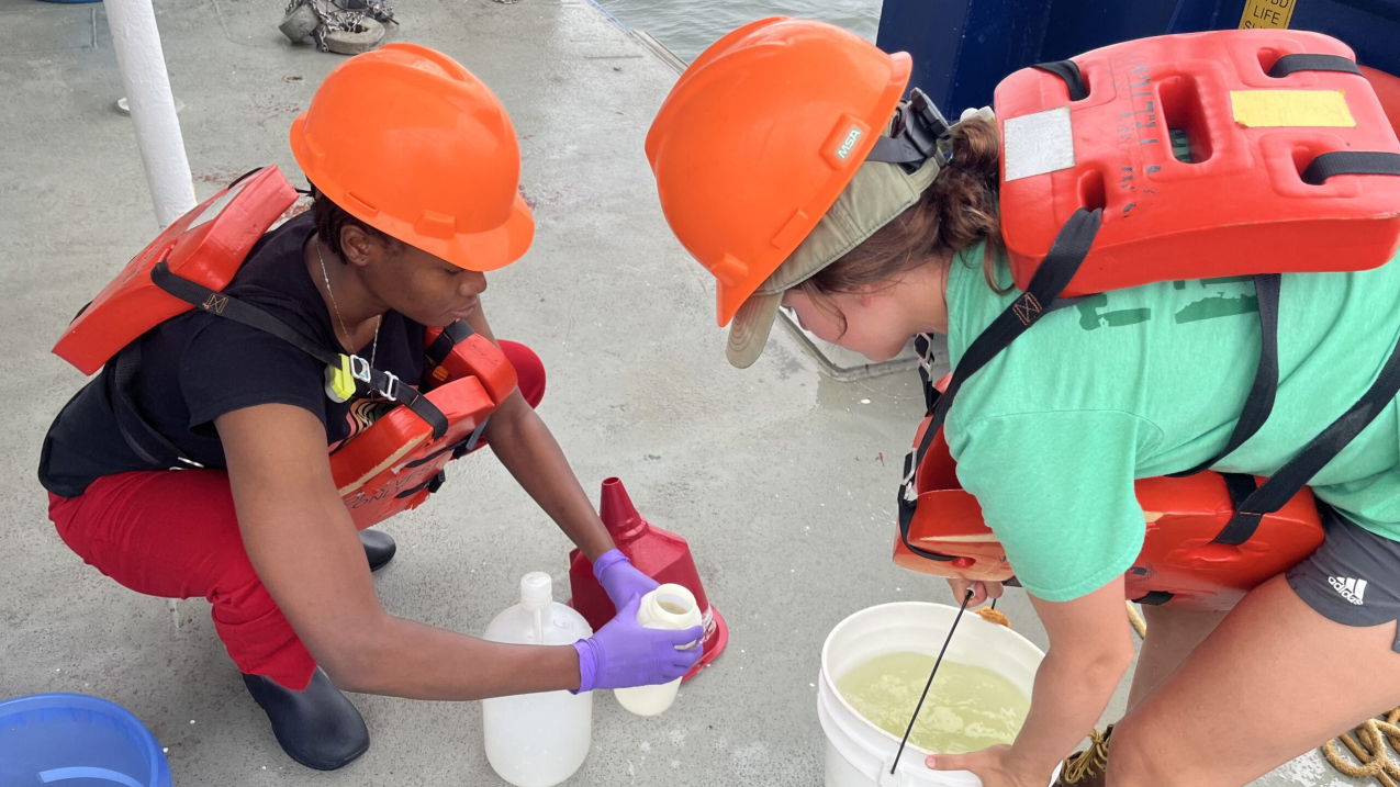 Photo showing scientists Chisom Emeghiebo and Dr. Jill Tupitza collect surface water samples aboard Research Vessel Pelican on July 17, 2024. The samples were collected as part of a NOAA-funded cruise measuring the Gulf of Mexico hypoxia "dead zone." (Credit: LUMCON/LSU)