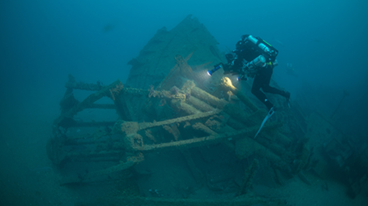 A scuba diver shines a light into the sunken steering quadrant of the Tamaulipas shipwreck.