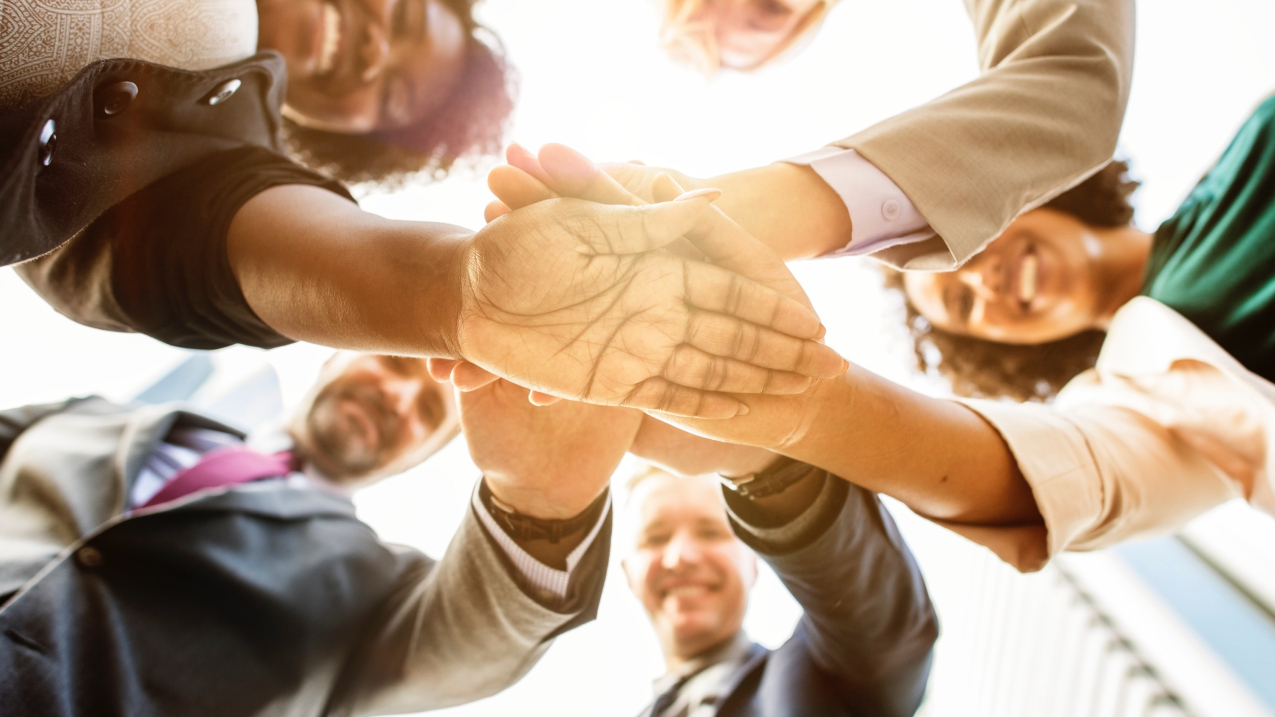 Group of business people creating a huddle. (shutterstock)