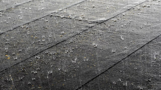 Close up of rain falling on a tiled roof. The rain looks to be falling hard.