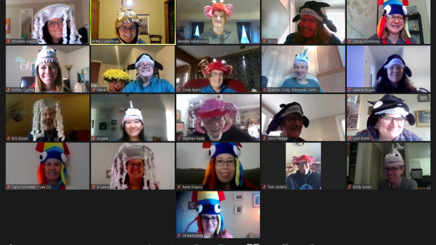 A screenshot of twenty-one adults wearing marine-themed hats participating in a Zoom call. Hats include jellyfish, squid, killer whales, crabs, an octopus, sharks, and an angler fish complete with an electric light on its lure.