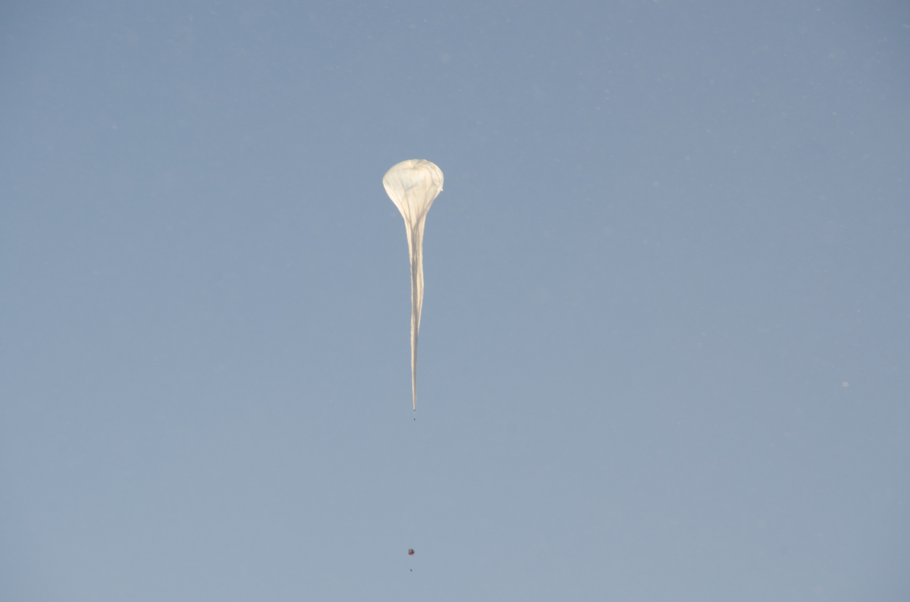 An ozonesonde balloon rises into a clear South Pole sky