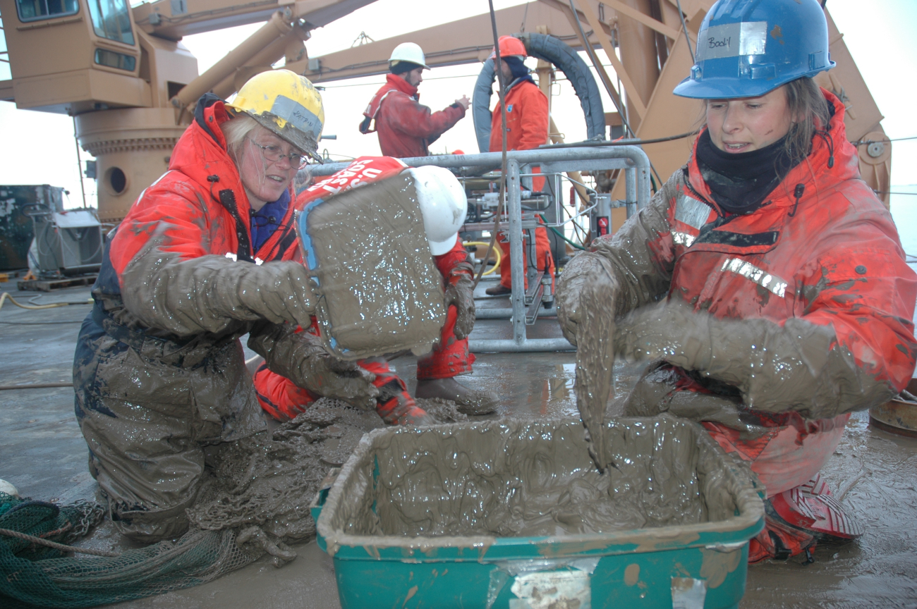 Katrin Iken (left) and Bodil Bluhm move deep-sea mud from the trawl netto a bucket