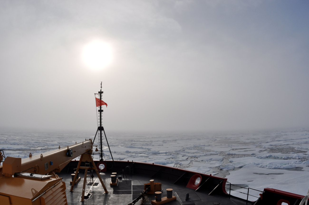 Sun seen through the clouds over the jackstaff as the CGC HEALY proceedsthrough ice floes