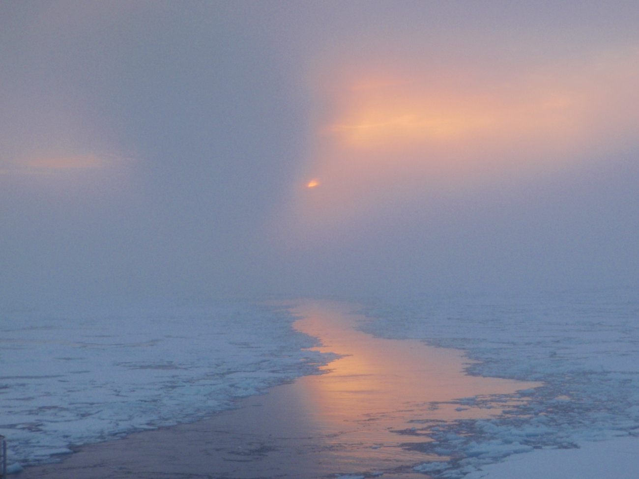 A glimpse of sun illuminating a lead through ice floes