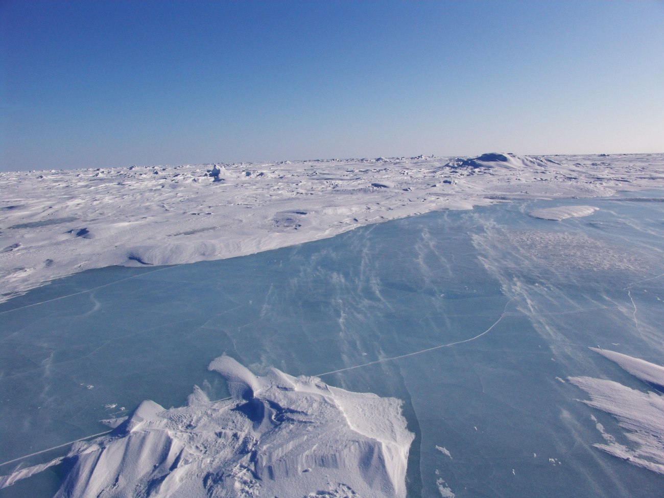 Looking over a frozen melt pond towards a hummocky ice landscape in multi-year ice