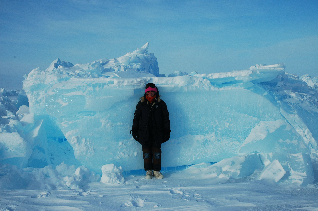 Scientist standing by block of ice for scale on pressure ridge