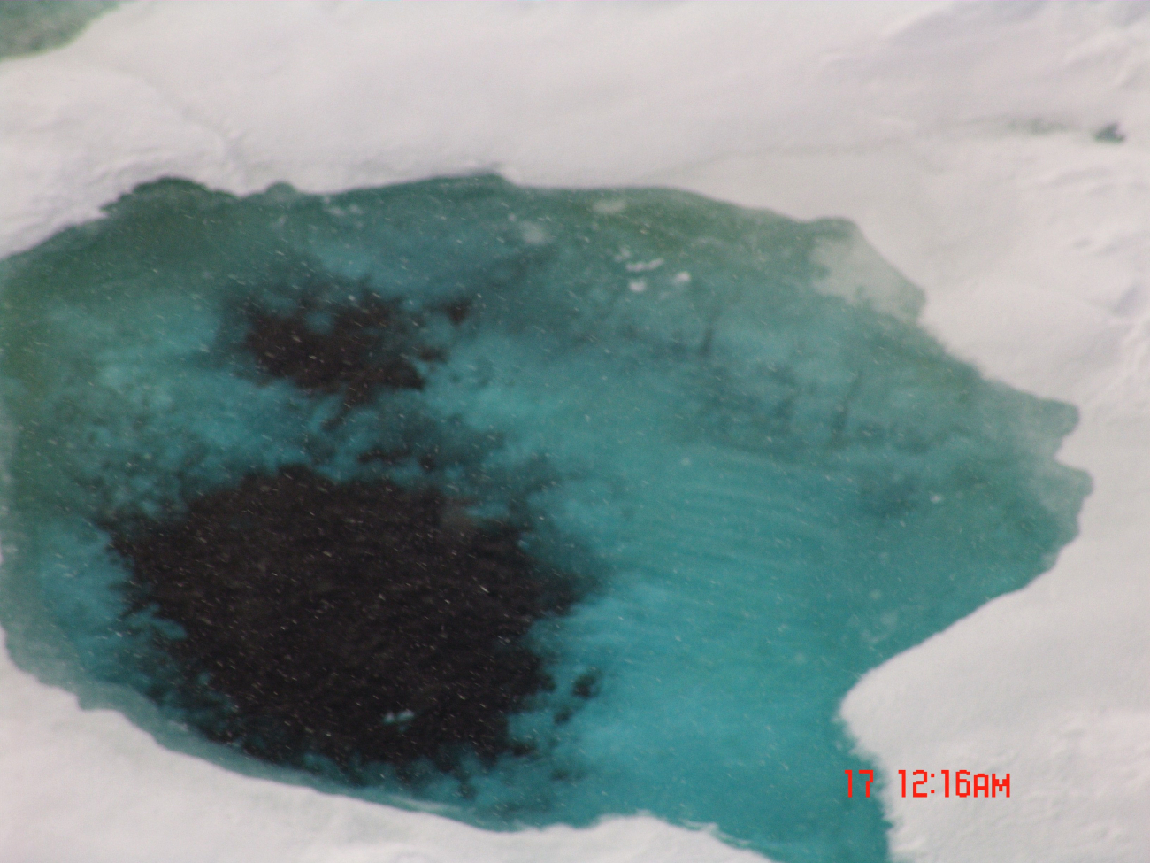 Looking down to aquamarine colored ice with melt ponds breaking through tounderlying seawater