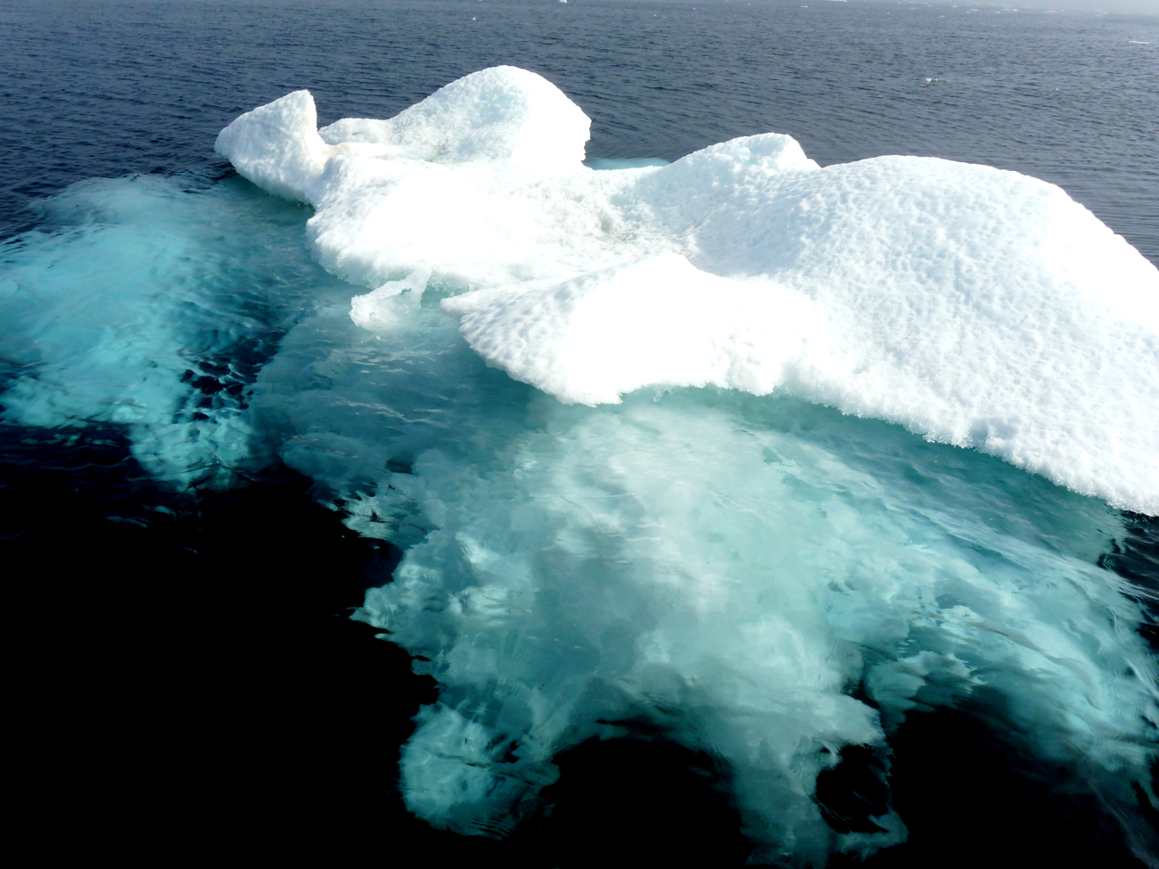 A small ice berg with its greater mass of ice visible below the surface