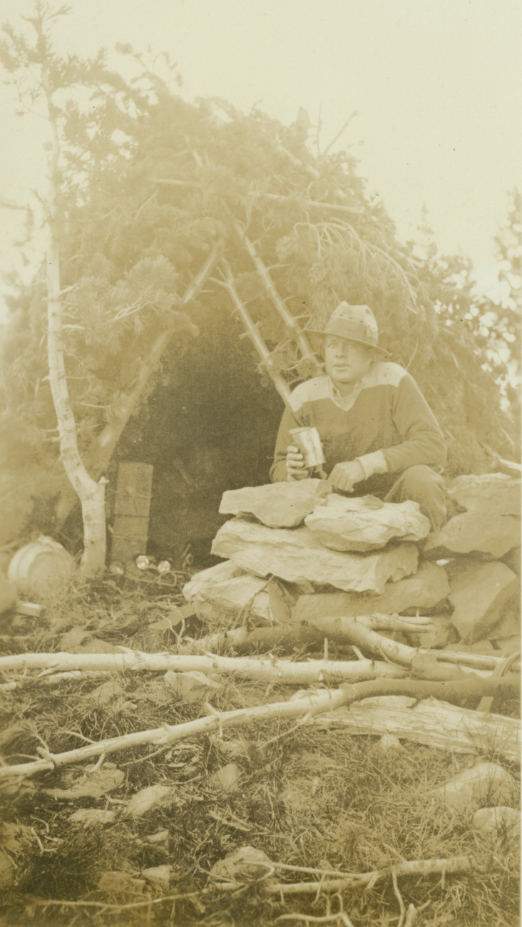 Cowboy Roy Bixby in front of a pine shelter erected by the observing party tokeep dry while waiting for a clear line of sight at Station Nevada on NevadaMountain
