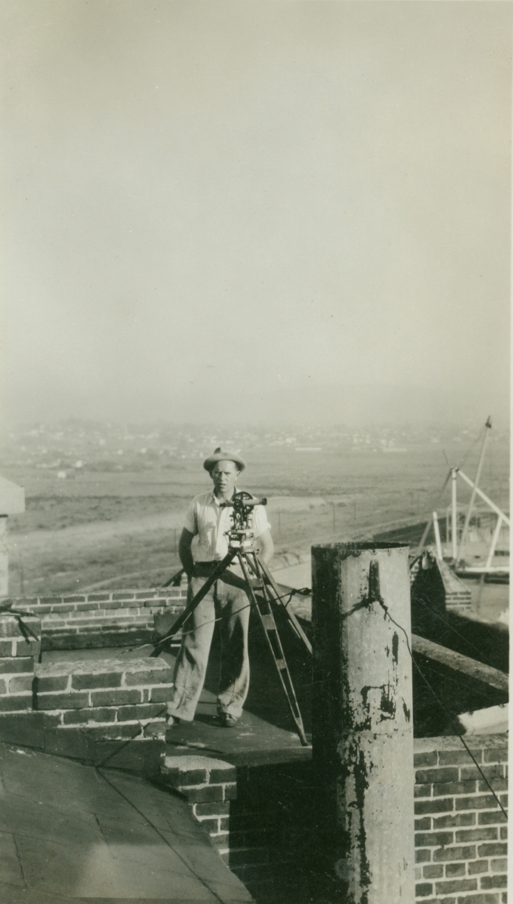 Floyd Risvold with theodolite on top of old brewery near the Navy destroyerpiers