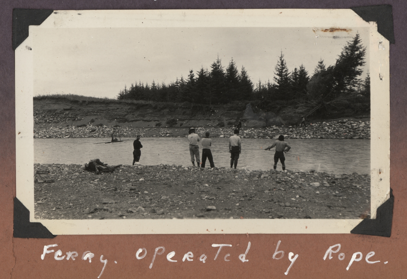 Work party crossing stream on improvised ferry operated by rope