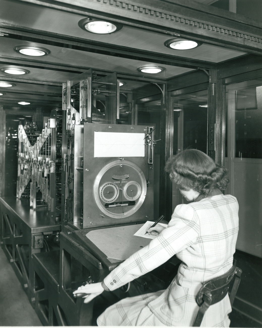 Woman operating Old Brass Brains, the mechanical tide computer that producedtidal predictions, sunrise and sunset tables, moonrise and phase of the moontables for thousands of locations around the globe