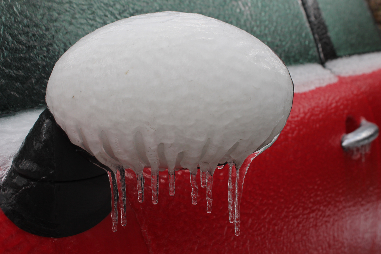 Freezing rain coats the rear view mirror of a car during an ice storm