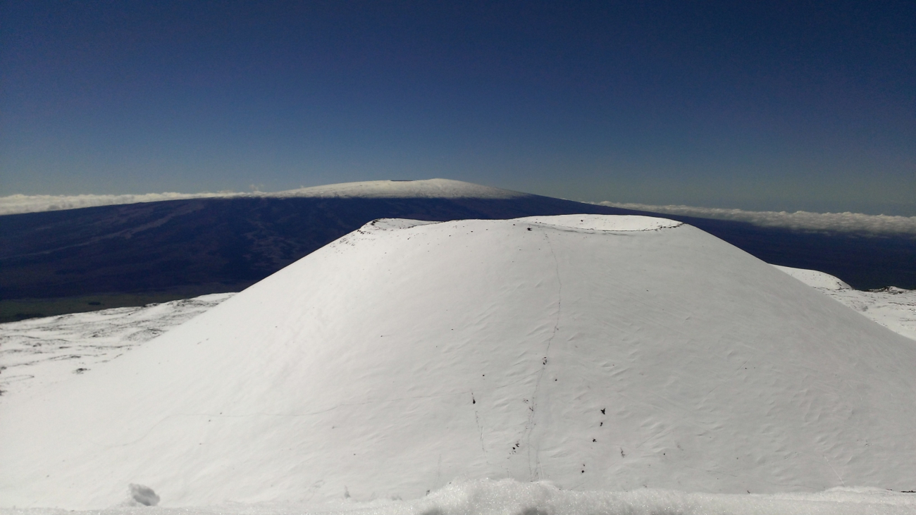 Snow covered cinder cone at the summit of Mauna Kea with snowcovered Mauna Loa in the background