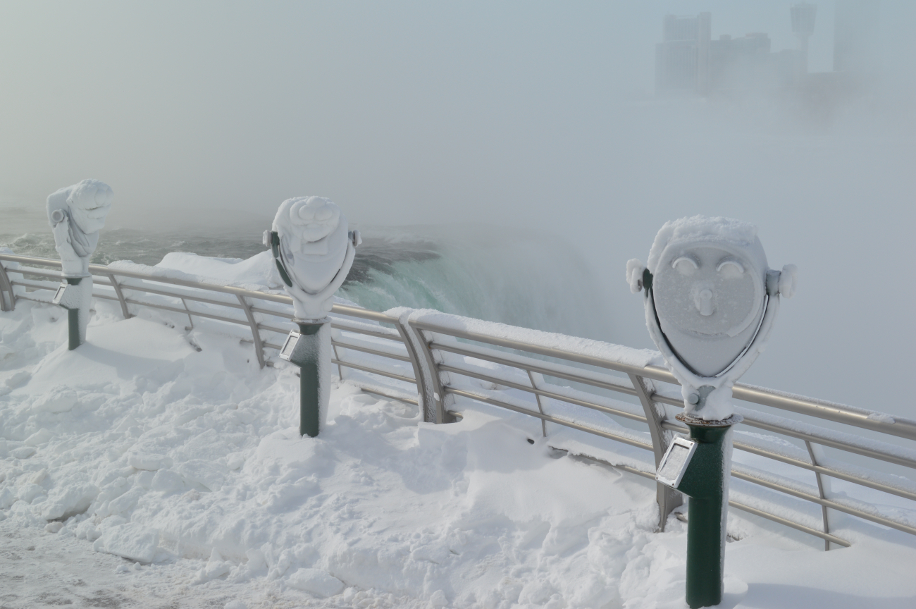The American Falls from behind frozen coin-operated binocular machinesduring a record coldest month in climate history for nearby Buffalo, New York