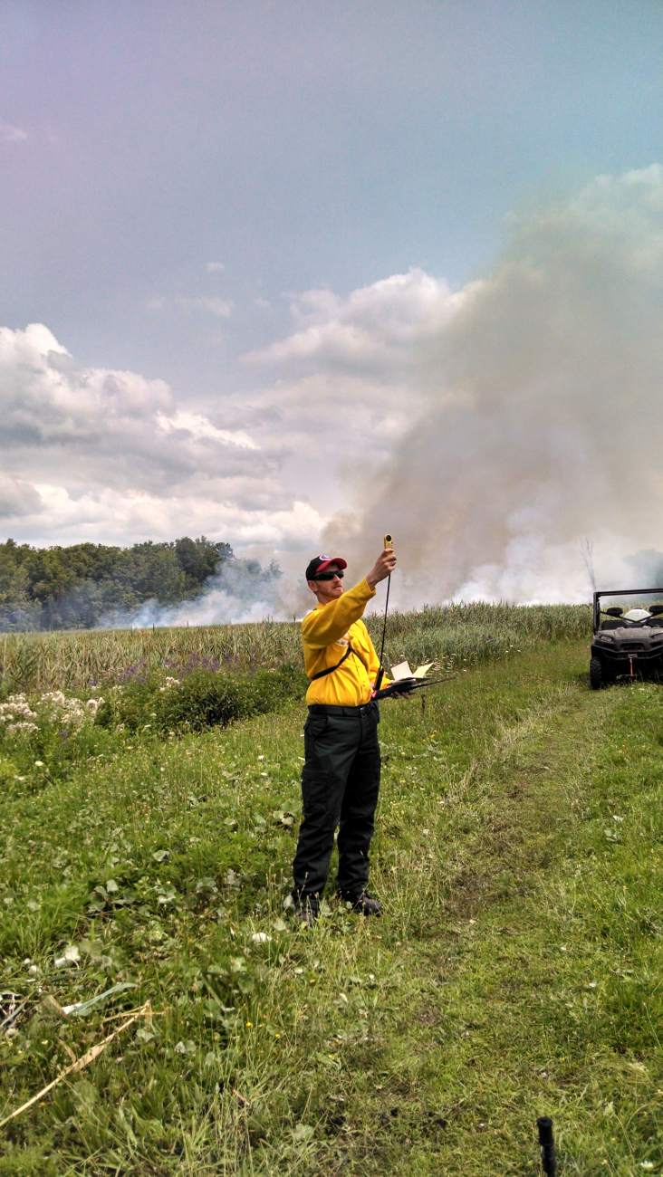 A meteorologist taking wind and humidity readings while supporting aprescribed burn at Iroquois National Wildlife Refuge