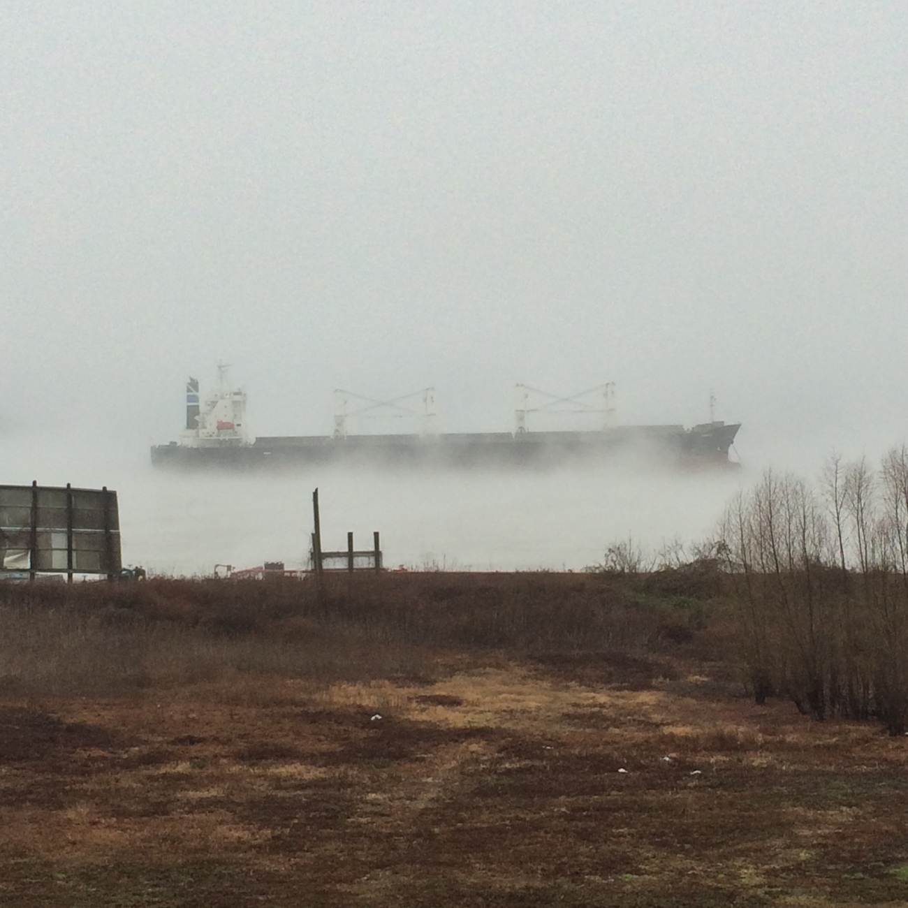 Morning fog hides all but the top of a ship travelling up the Mississippi River