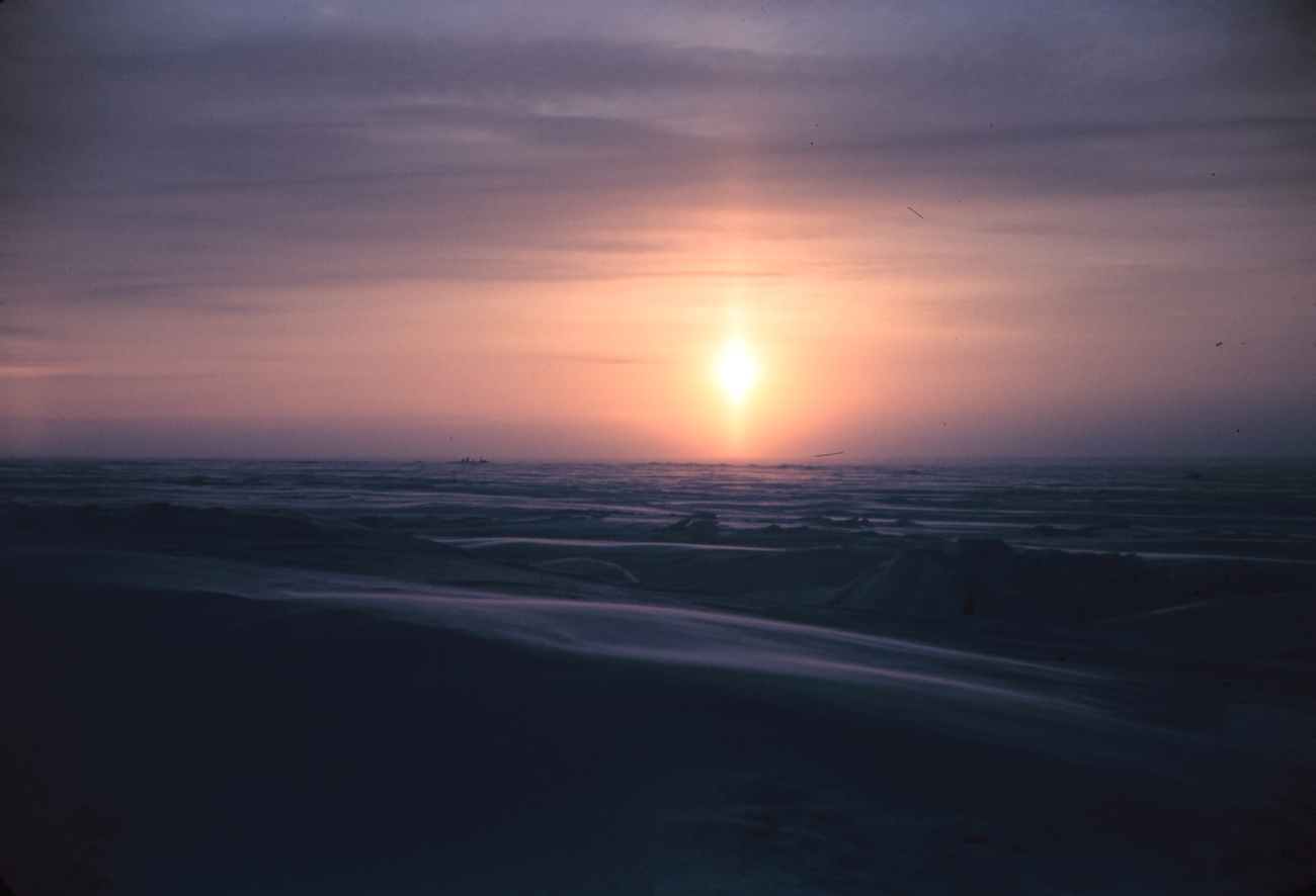 A sun pillar forms as the sun rises over the Arctic plain