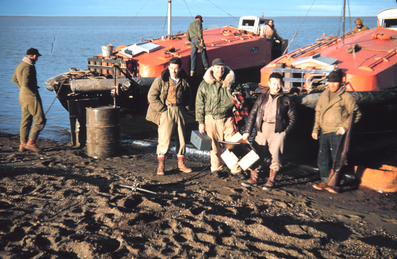 Launch crews with their boats - Lieutenant Commander Marv Paulsonin green coat in center