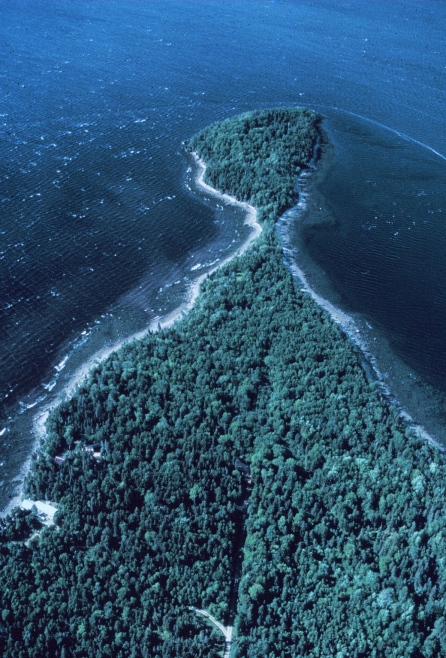 Apparently a tree-covered  peninsula with a rocky shoreline