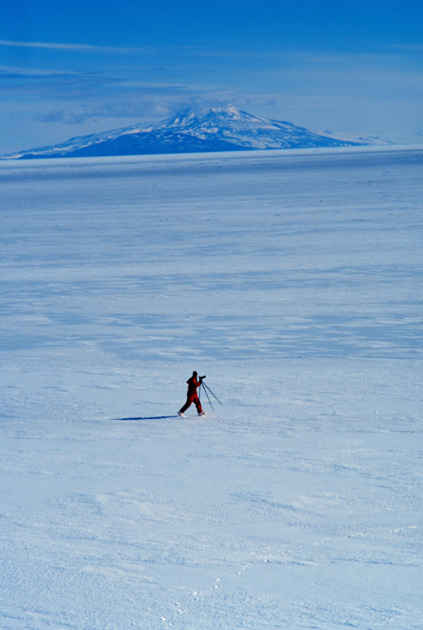 Photographer getting ready to set up for shot of Mount Erebus across sea ice