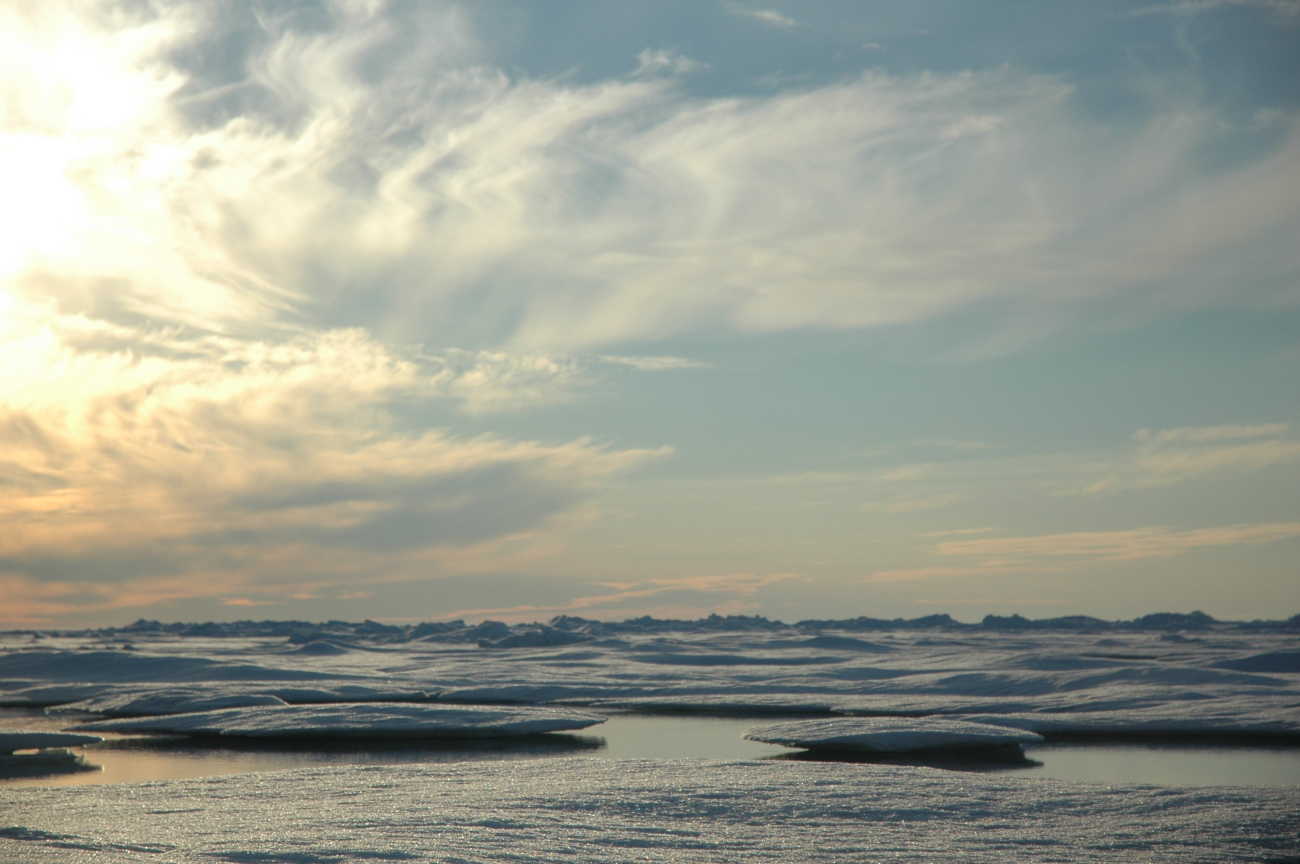 Multi-year ice floes and numerous cloud layers with the sun low on the horizon