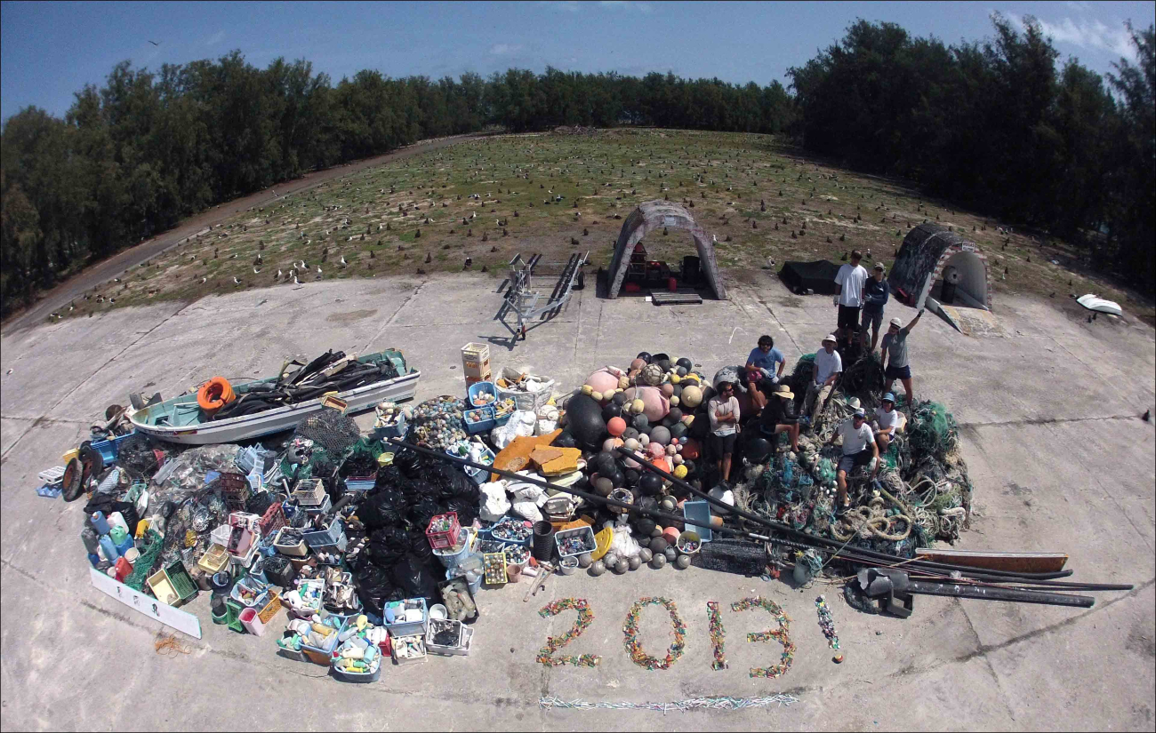 James Morioka, Kerrie Krosky, Kristen Kelly, Tomoko Acoba, KevinO'brien, Kerry Reardon, Edmund Coccagna, Joao Garriques, and Russell Reardon(Clockwise from UR) atop a large 14 ton (13,795 kg)  pile of derelict fishinggear and plastic debris collected during a 21-day mission at Midway Atoll