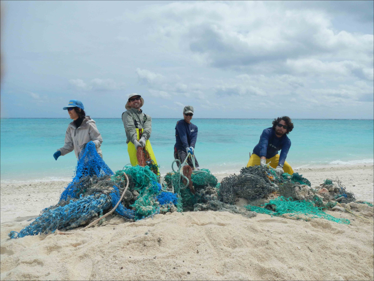 Tomoko Acoba, Russell Reardon, Kerrie Krosky, and Joao Garriquesremove a large, buried derelict fishing net from the beach at Eastern Island