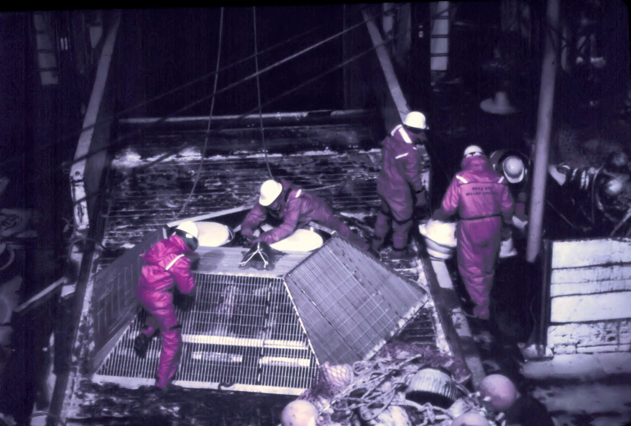 Deploying a large fish trap or crab pot from the MILLER FREEMANduring night operations