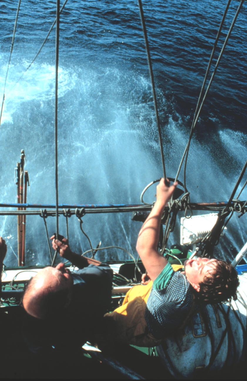 One fisherman holds the pole from the deck while another, higher up, pulls theattached cord when the tuna takes the bait