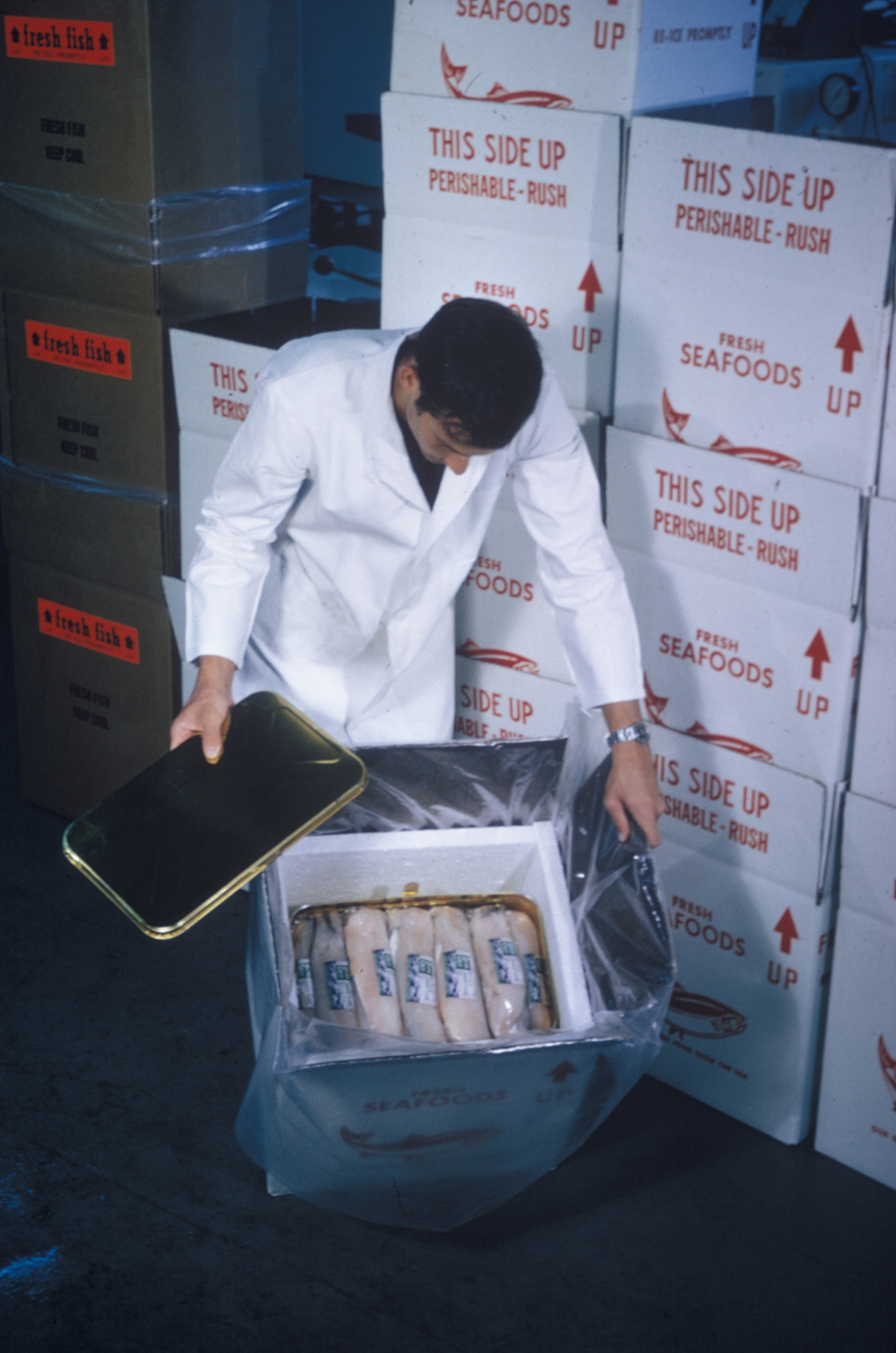 A technician is packaging fish fillets in a plastic container for demonstrationshipping tests