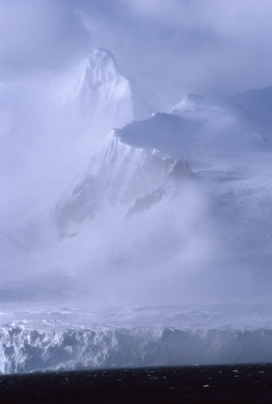 Snow-shrouded mountain peaks rising seen through storm clouds