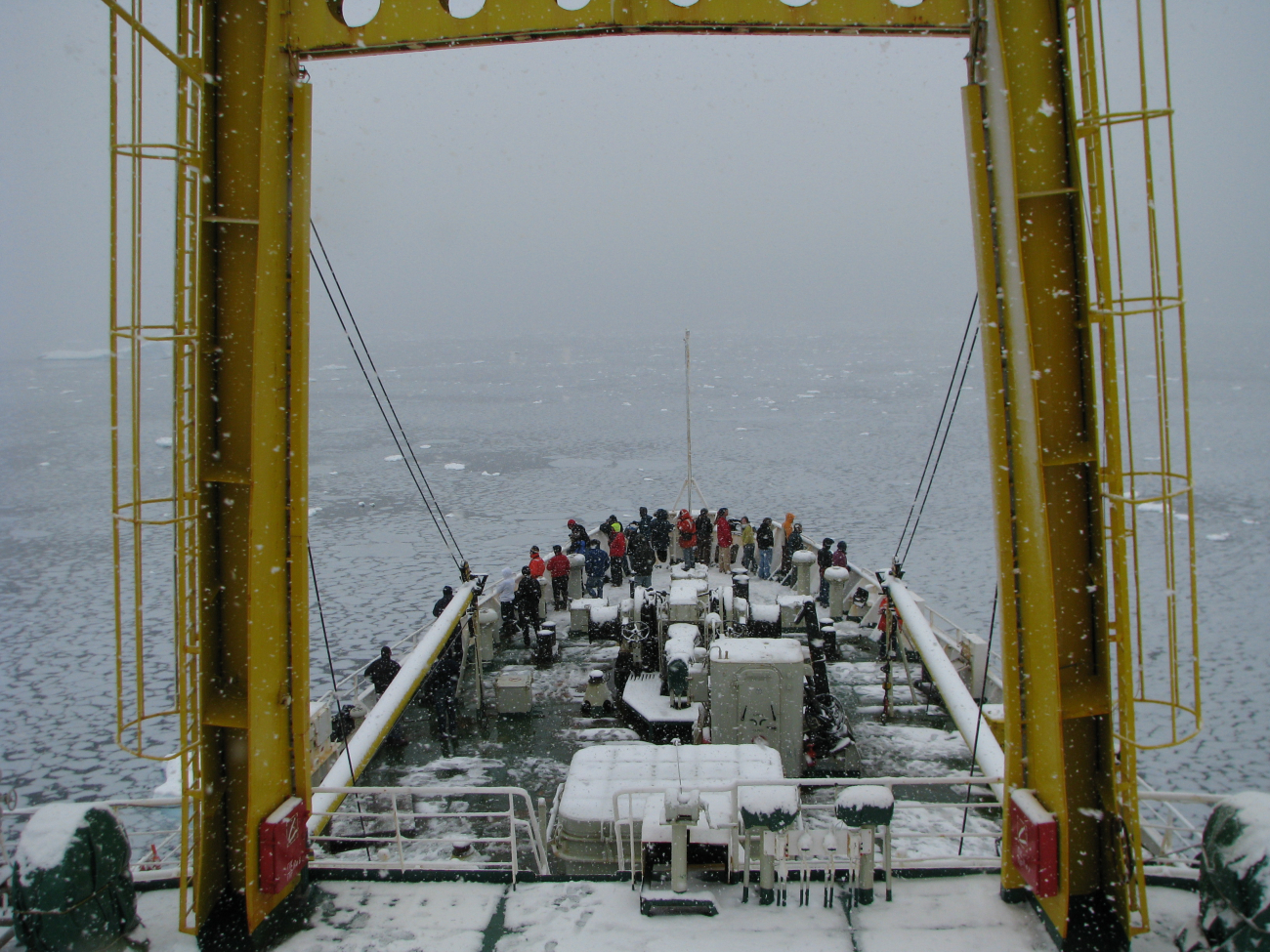 AMLR scientists and Russian crew peer over the bow of the R/VYuzhmorgeologiya as the ship slowly makes it way through icy watersin an Antarctic snowstorm