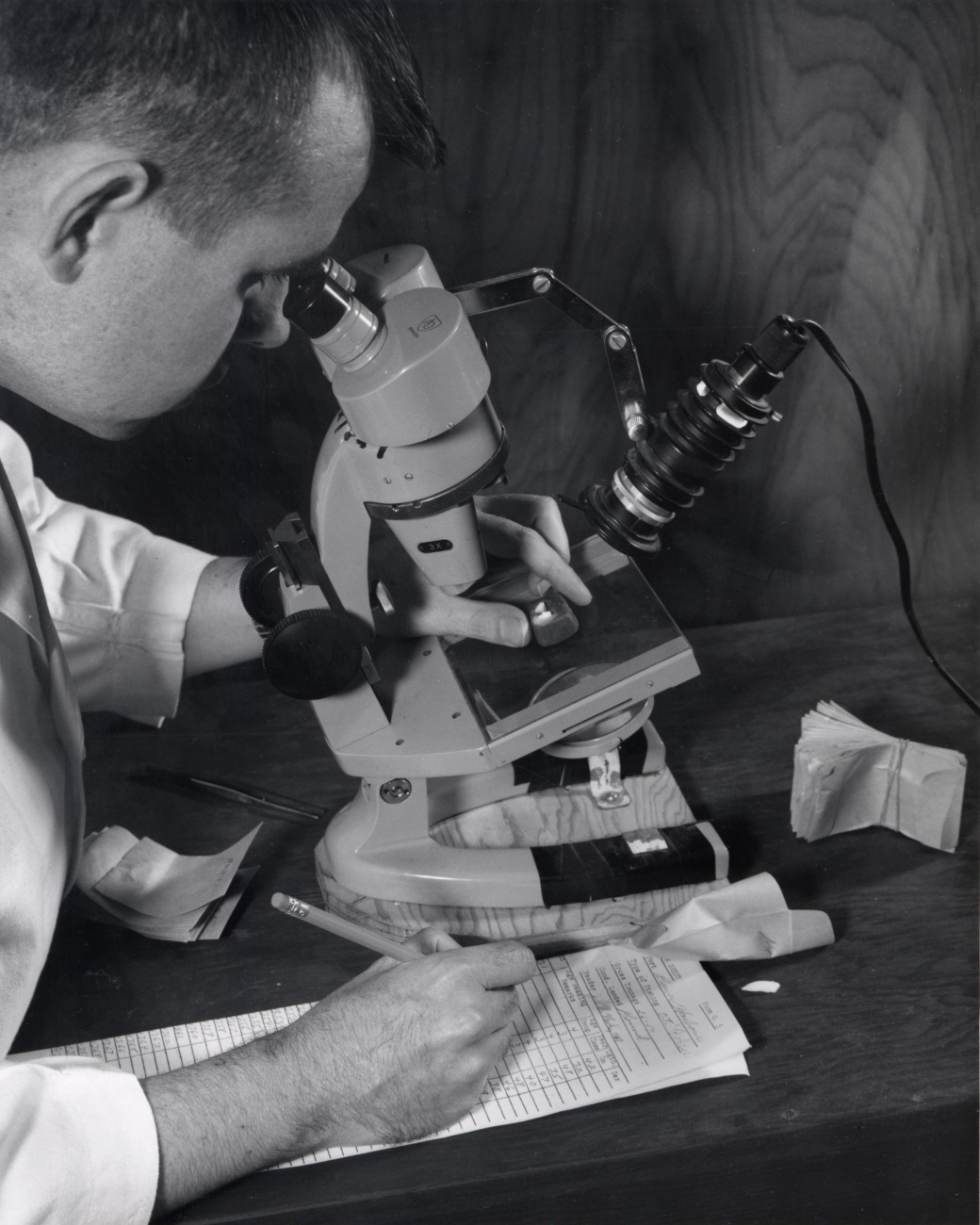 A biologist examining a specimen through a microscope