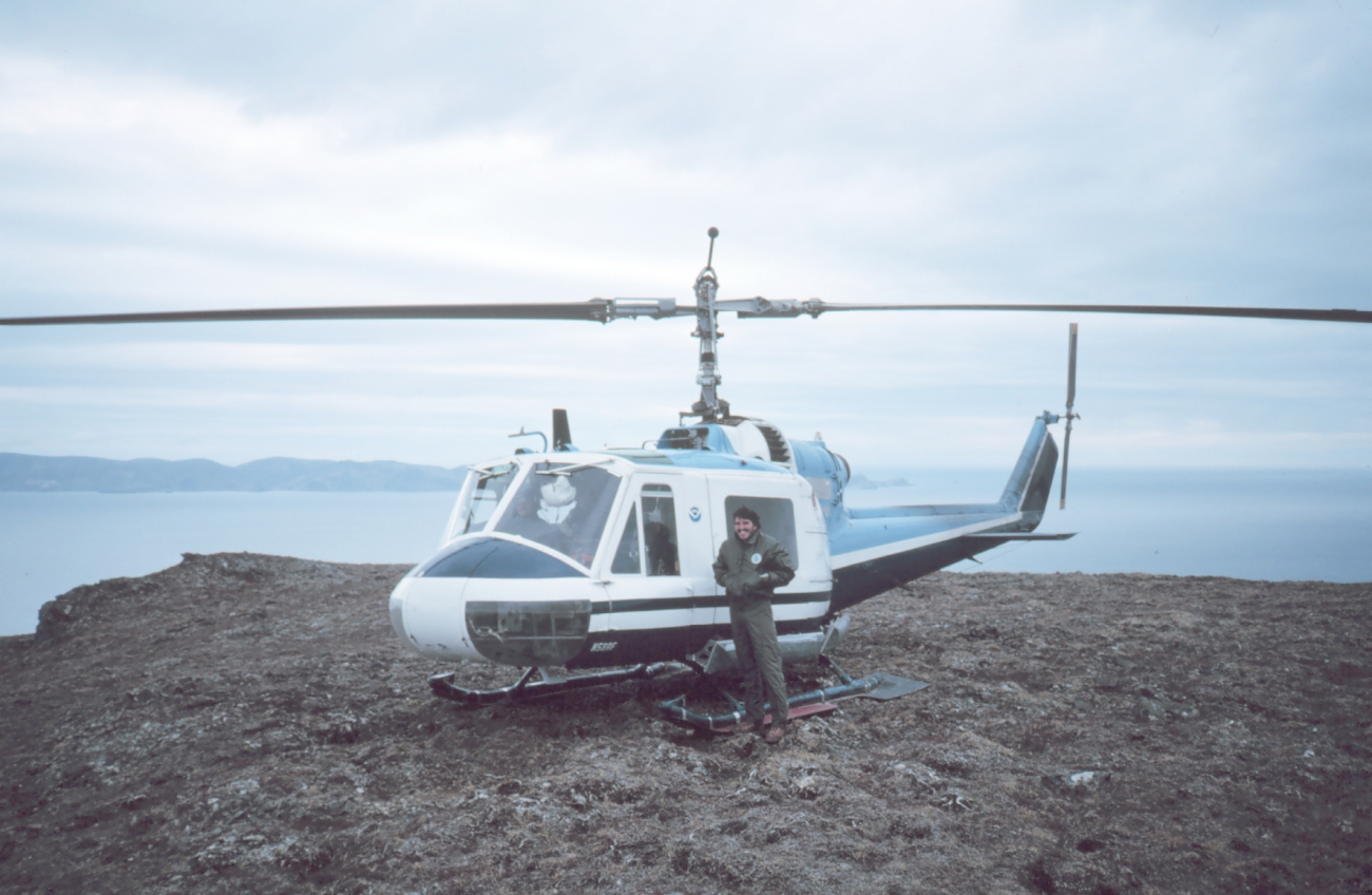 Helicopter mechanic alongside Bell helicopter supporting geodetic operations onthe Alaska Peninsula
