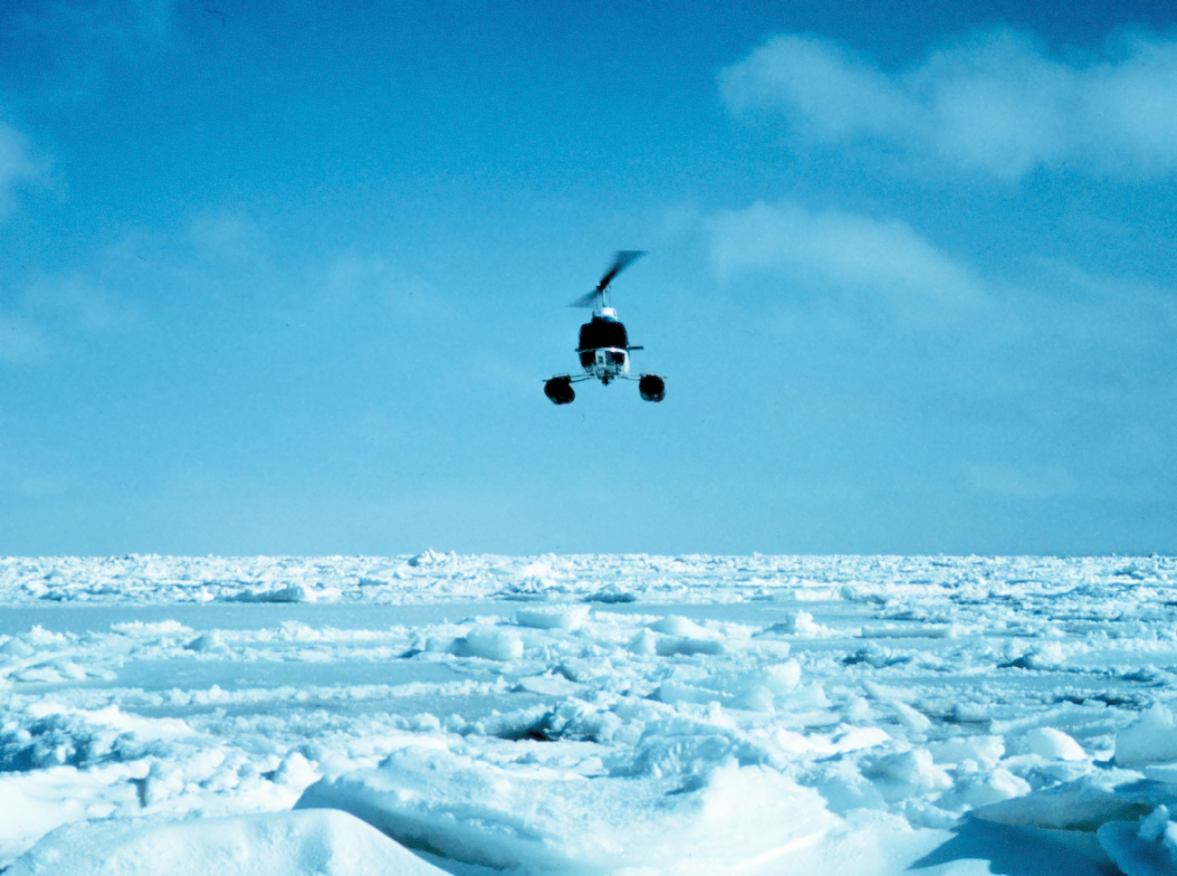 Bell helicopter operating over the ice floes of a frozen Bering Sea