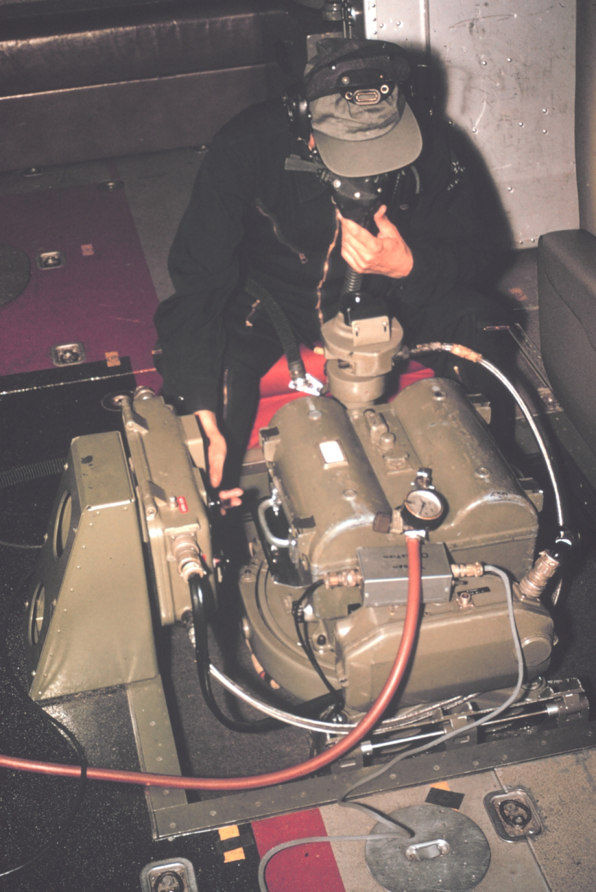 Aerial photographer in unpressurized cabin of NOAA de Havilland Buffalobreathing with assistance of oxygen mask, operating Wild RC-8 camera