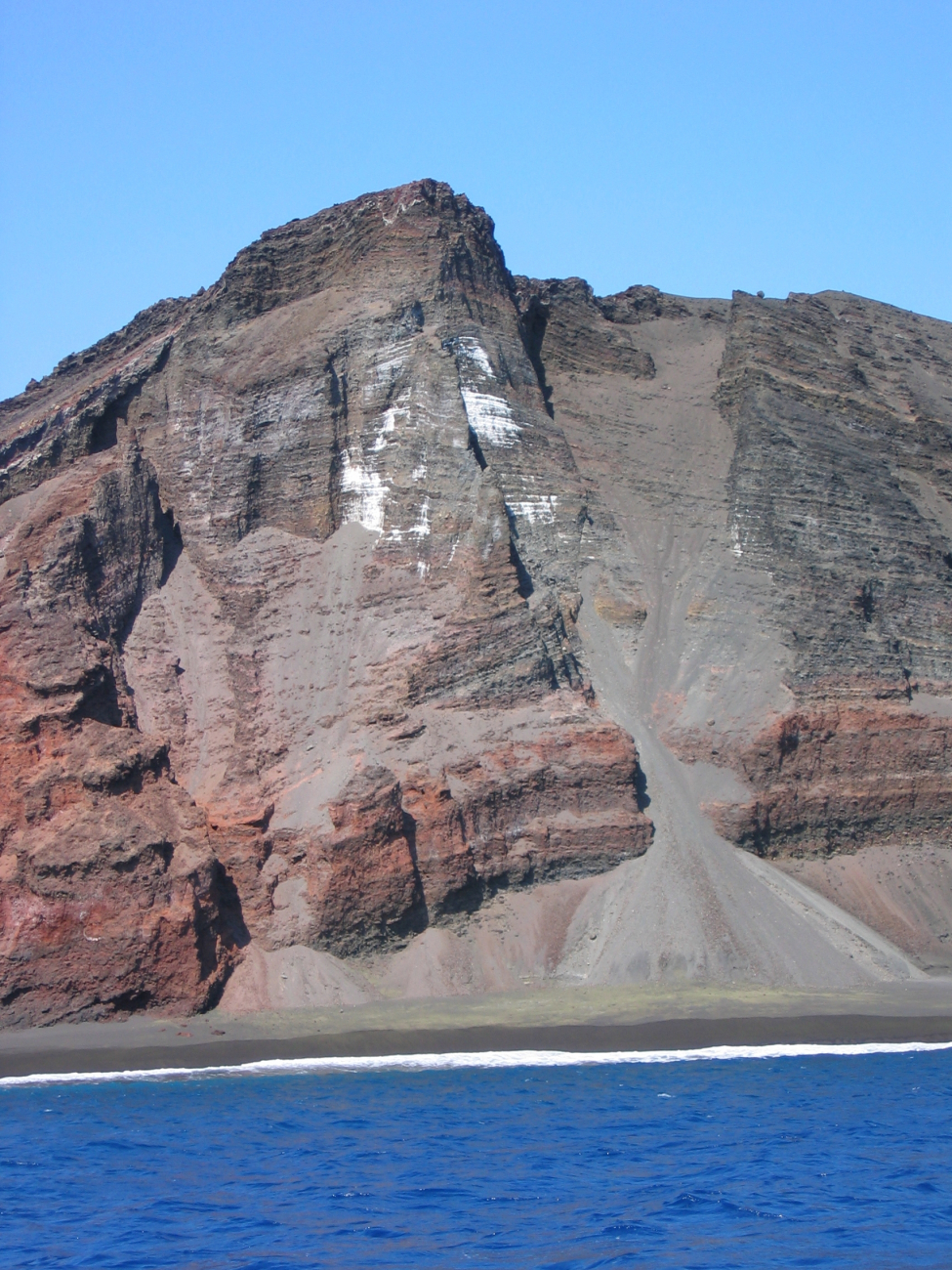 Interior structure of an eroded volcanic cone where it meets the sea