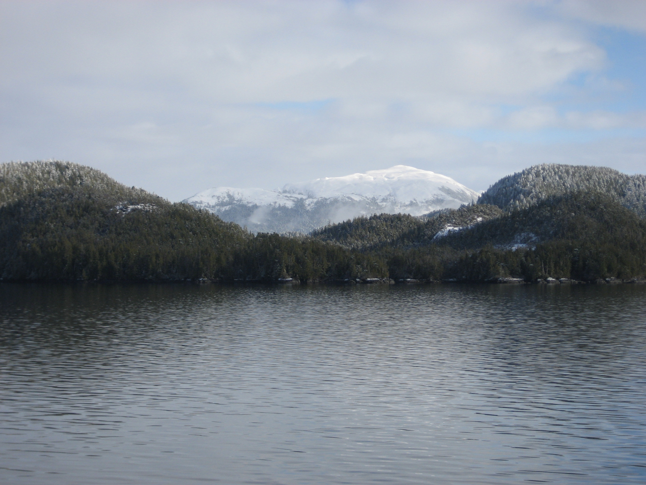 A sprinkling of snow at water level with mountains covered at higher elevations