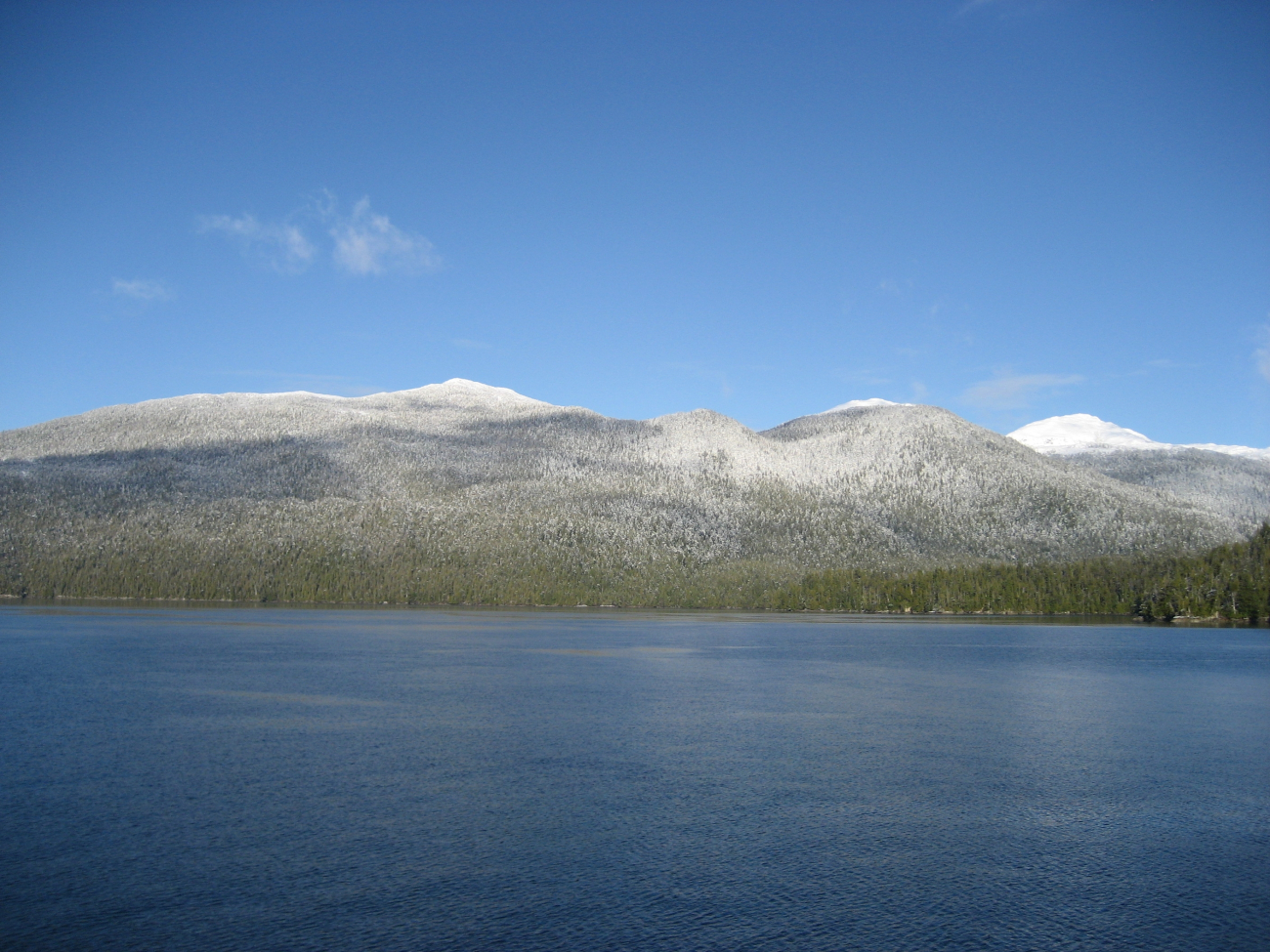 A sprinkling of snow at water level with mountains covered at higher elevations