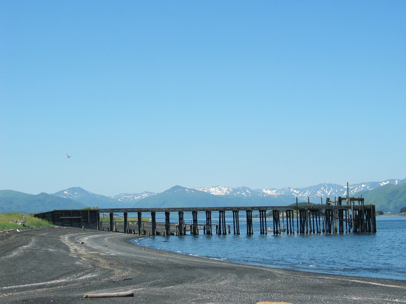 Black sand and cobble beach on Kodiak Island with pier at low tide