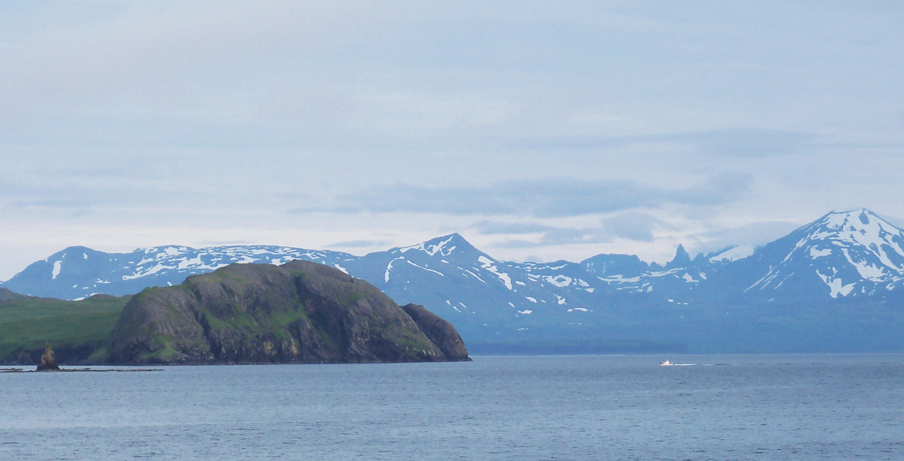 A Coast Survey survey launch dwarfed by the Pavlof Islands and the mountains ofthe Alaska Peninsula