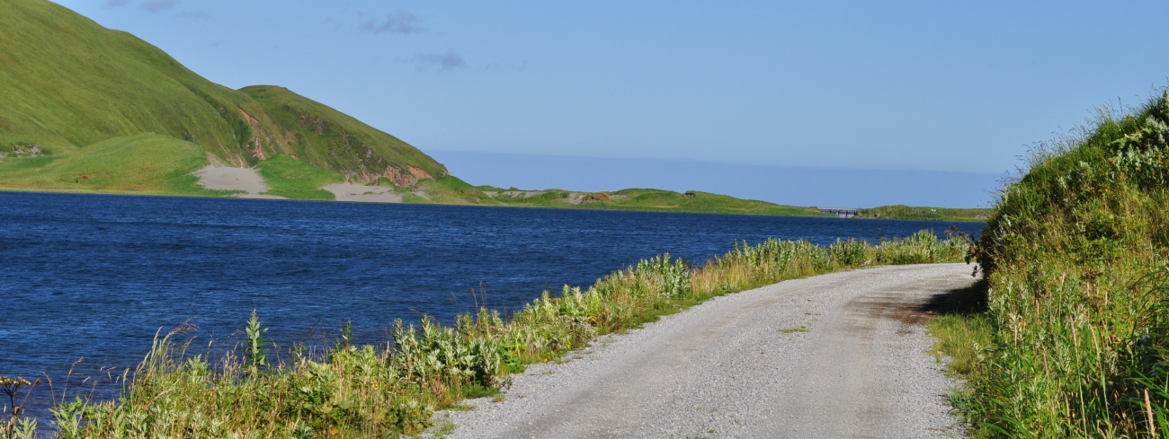A gravel road running along the shoreline on a clear sunny day