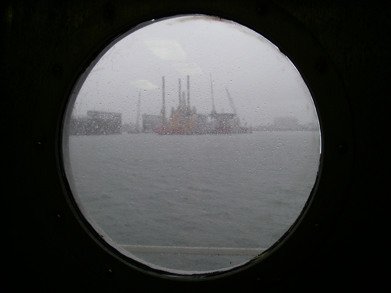 Looking through the porthole on a rainy day at jackup rigs in Galveston harbor
