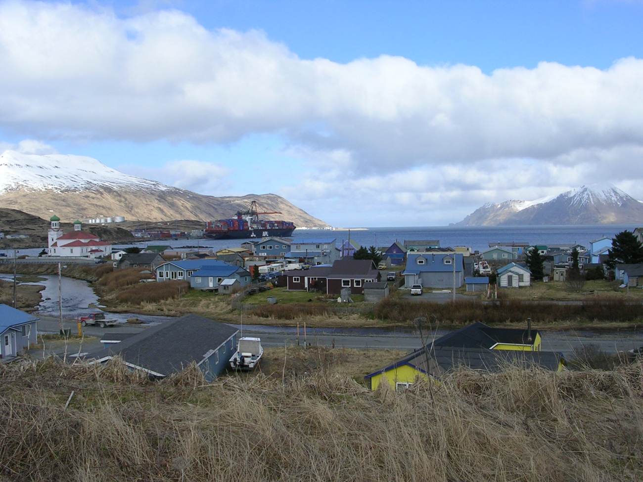 Residential district of Dutch Harbor with the old Russian Orthodox Church andthe American President Lines container dock in the middle distance