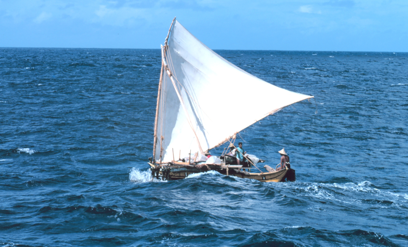 A Micronesian outrigger sailing proa or under sail