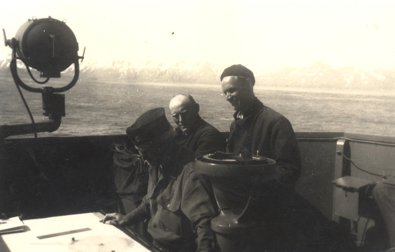 Commander William Malnate at navigator's table with Boatswain Peterson incenter and Lt