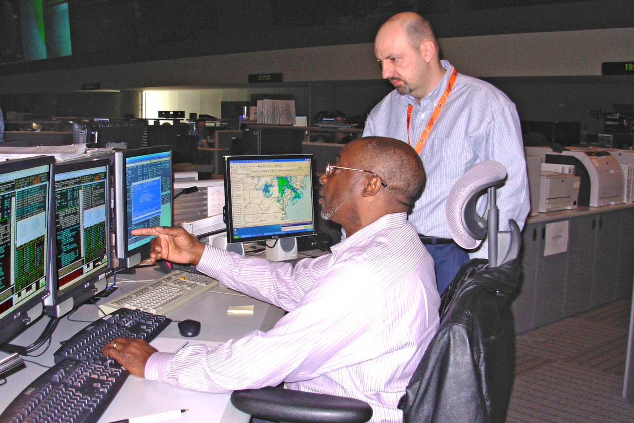NOAA NESDIS employees Al Williams (seated) and Tom Boyd monitoring GOES-11spacecraft from the NESDIS Satellite Operations Center